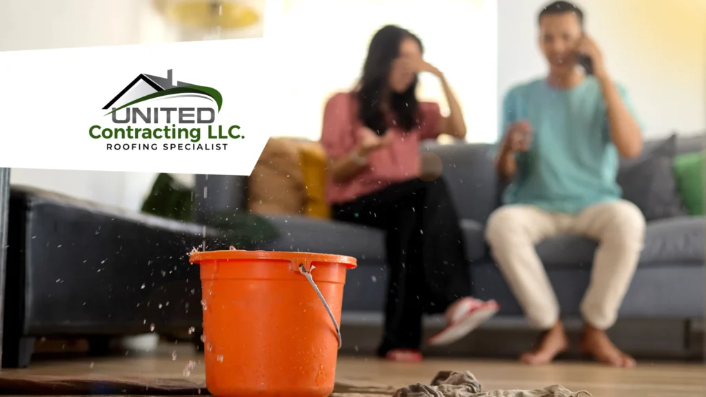 Close-up of a bucket on the floor collecting water droplets falling from a leak in the ceiling, indicating a water leak problem. In the background, out of focus, a couple can be seen, suggesting the impact of the leak on the house.